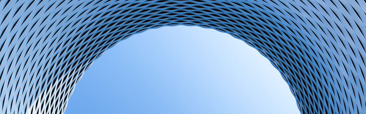 curved architectural detail on modern building featuring a basket weave design against a blue sky