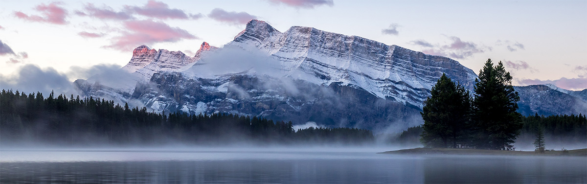 Mist-shrouded lake with a snow-capped mountain in the background