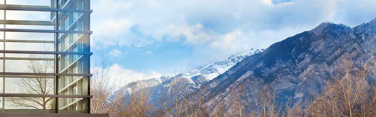 windows of a corporate building in  front of a mountain range